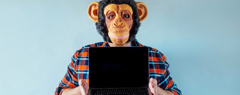 Ein Mann mit einer Affenmaske hält einen Laptop hoch. Das Bild symbolisiert Monkey Work, einfache, repetitive Aufgaben am Computer, im Gegensatz zu anstrengender Donkey Work.